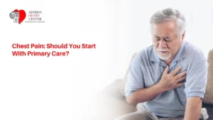 An older man sitting on a couch, grimacing in discomfort with his hands clutching his chest, featuring text that reads "Chest Pain: Should You Start With Primary Care?" and the Athens Heart Center logo.